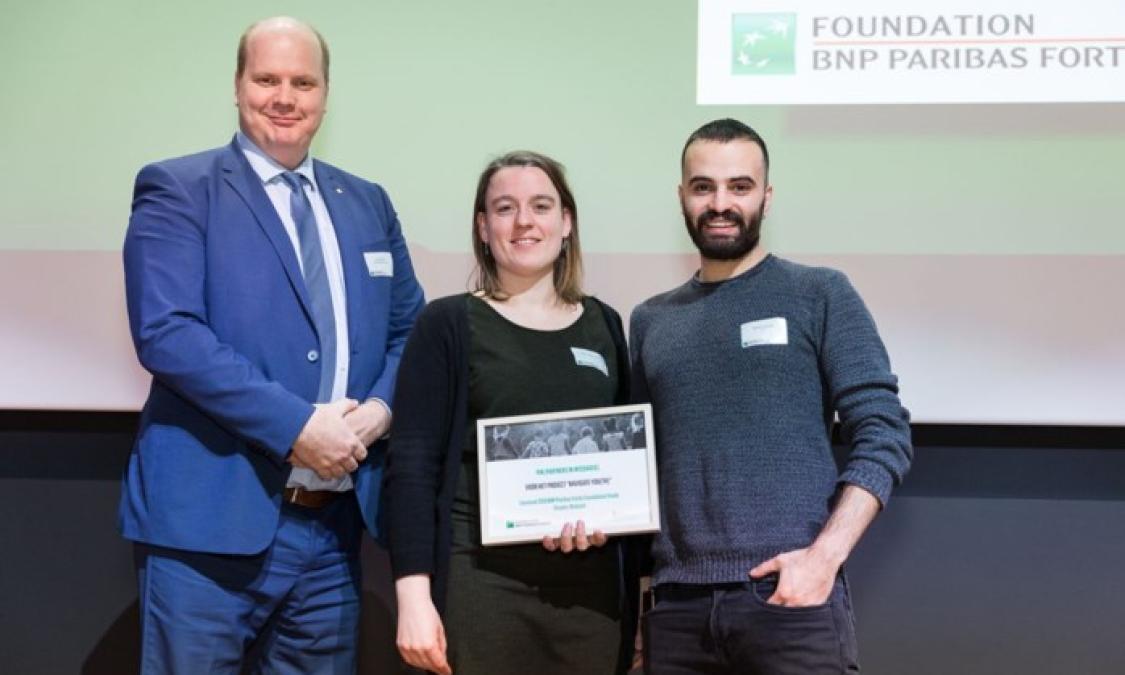 Twee medewerker van PIN poseren samen met een medewerker van BNP Paribas Fortis Foundation met de award in de hand.
